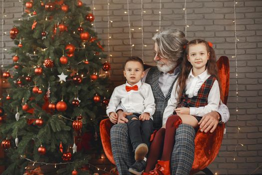 Family, holidays, generation, christmas and people concept . Children in a room decorated for Christmas on the background of a Christmas tree.