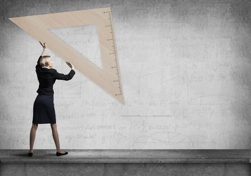 Woman holding big ruler on wall background. Testing and examination concept. Businesswoman measuring something with ruler. Human resources recruitment. Creative motivation, coaching and mentoring.
