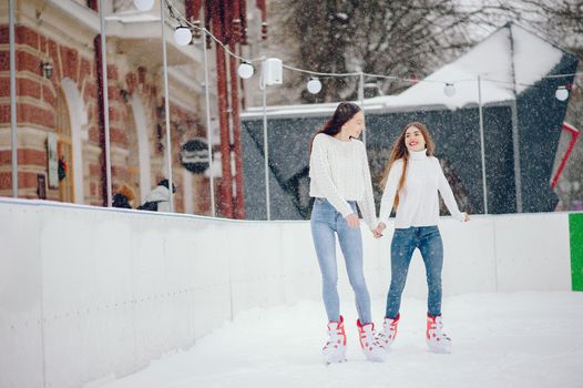 Girls in a winter city. Beautiful ladies in a white sweater. Women in a ice arena