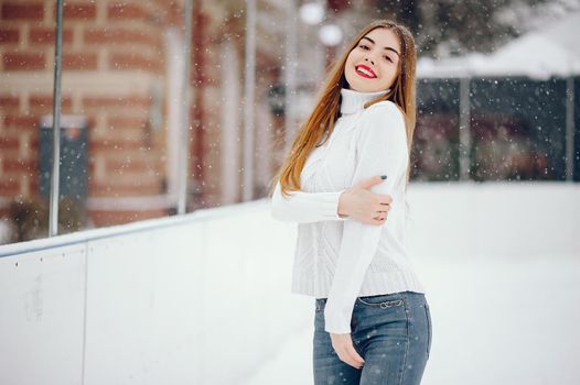 Cute girl standing in a winter city. Woman in a white sweater.