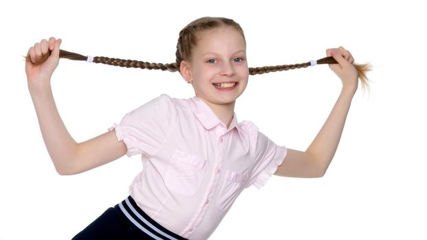 A beautiful little girl is pulling herself in pigtails. The concept of education, advertising, children's emotions. Isolated on white background.