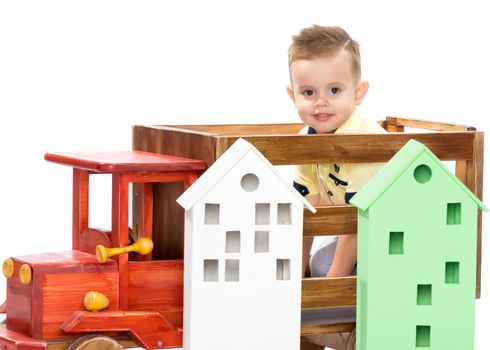 Cute little boy is playing with a toy wooden car on a white background in the studio. The concept of a happy childhood, learning and education in the family. Isolated.