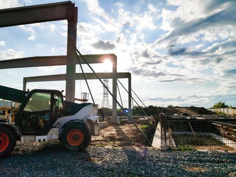 excavator on new construction site, in the background the blue sky and sun