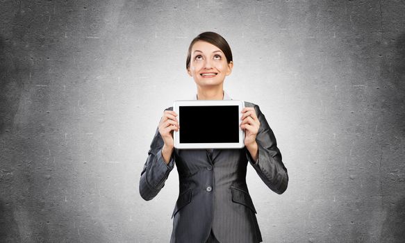 Businesswoman with tablet computer looking upwards. Portrait of happy smiling woman in formalwear show tablet PC near her face. Corporate businessperson and digital technology layout with copy space