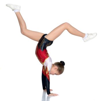 The girl gymnast performs a handstand with bent legs.The concept of childhood, sport, a healthy lifestyle. Isolated on white background.