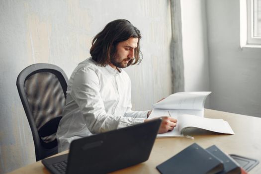 Handsome man in a white shirt. Businessman working at the office. Guy with a laptop.