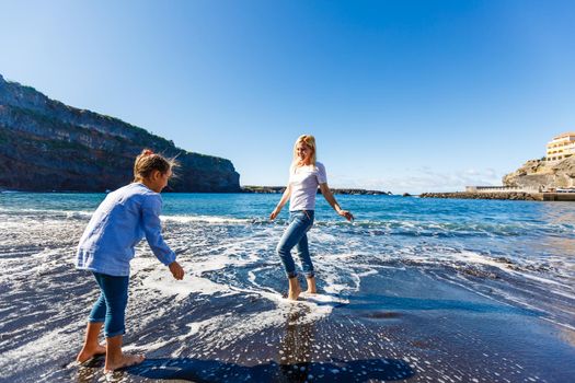 Family holiday on Tenerife, Spain. Mother with children outdoors on ocean. Portrait travel tourists - mom with kids. Positive human emotions, active lifestyles. Happy young family on sea beach