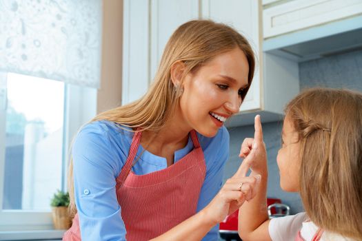 Beautiful mother and her adorable daughter having fun in the kitchen while cooking food at home