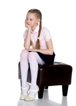 Beautiful schoolgirl girl with long pigtails sitting on the couch. The concept of school fashion, children's emotions. Isolated on white background.