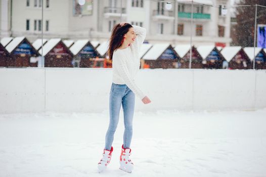 Girl in a winter city. Beautiful lady in a white sweater. Woman in a ice arena