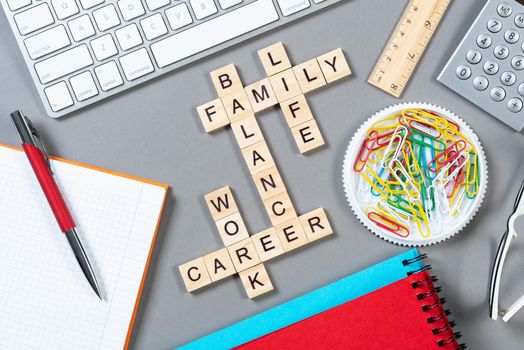 Business motivation concept with words from cubes. Still life of office workplace with crossword. Flat lay grey surface with computer keyboard and stationery. Strategy planning and business analytics.