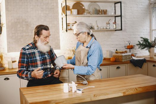 Old couple in a kitchen. Woman in a blue shirt and aprone.