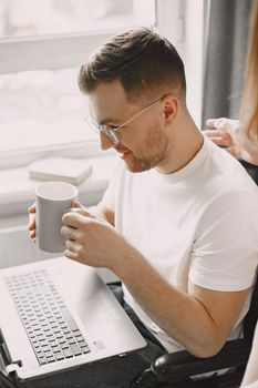 Disabled man using laptop. Cheerful handsome man stay at home and work remotely. The girlfrind cheering up her boyfriend.