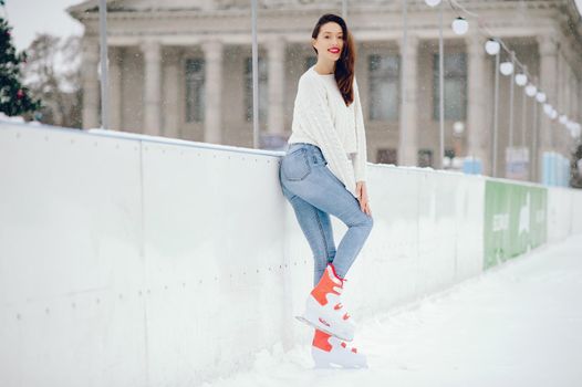 Girl in a winter city. Beautiful lady in a white sweater. Woman in a ice arena