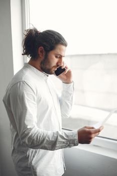 Handsome man in a white shirt. Businessman working at the office. Guy with mobile phone.