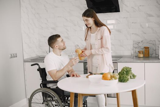 Woman with disabled man in wheelchair having breakfast together at home.