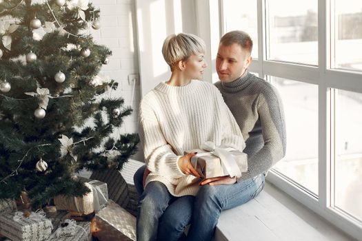 Family at home. Couple near christmas decorations. Woman in a gray sweater.