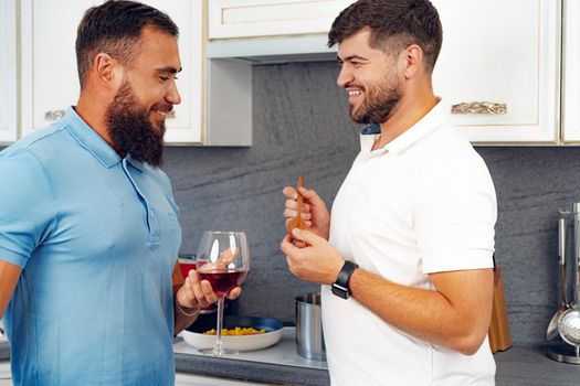 Happy homosexual couple preparing food together in kitchen at their house