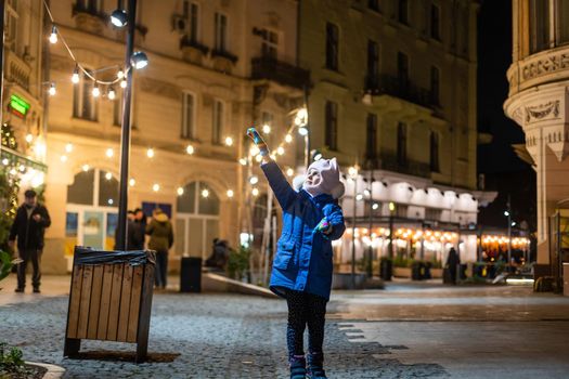 Little girl, iluminated with street lights. Christmas decoration is in the background.