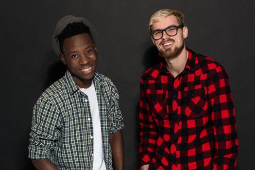 Studio lifestyle portrait of two best friends hipster boys going crazy and having great time together. On black background. Belt portrait