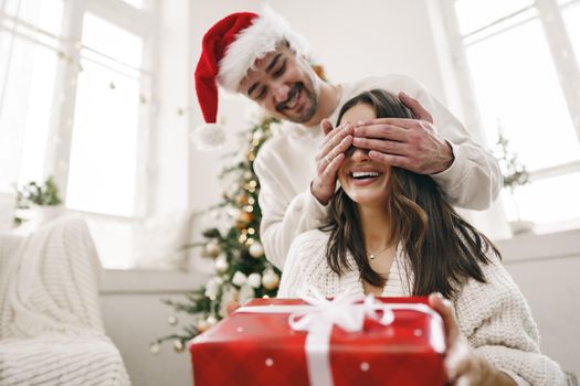 Young cheerful couple in love with present for Christmas, portrait