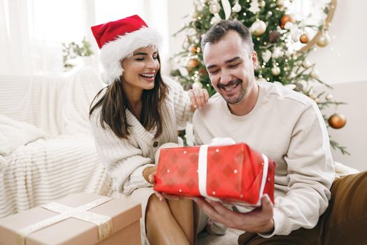 Young cheerful couple in love with present for Christmas, portrait