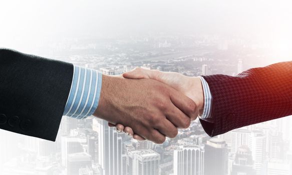 Close-up of the handshake of businessmen. Against the backdrop of the cityscape