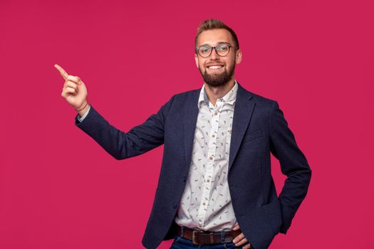 Portrait view of an attractive happy businessman with glasses on a pink background. Studio shot. Copy space