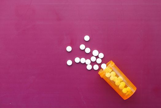 white color medical pills spilling on pink ,
