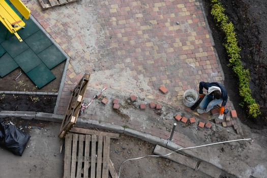 Improvement of the courtyard paving slabs, unfinished work on laying paving slabs. Laid new paving slabs sprinkled with sand and heaps of figured tiles ready for installation