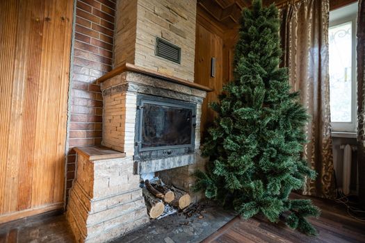 Photo of interior of room with a wooden wall, Christmas tree, fireplace. Christmas atmosphere. Home comfort