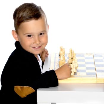 Little boy is playing chess on a white background. The concept of a happy childhood, the harmonious development of the child in the family. Isolated.