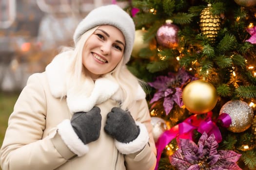 holidays and people concept - beautiful happy young woman over christmas tree lights in winter evening