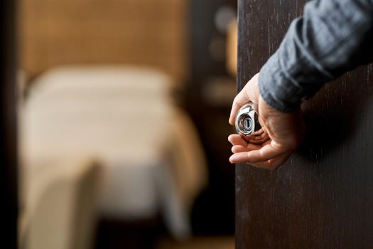 Cropped photo of man opening door to hotel room after cleaning. Hotel service concept. Copy space