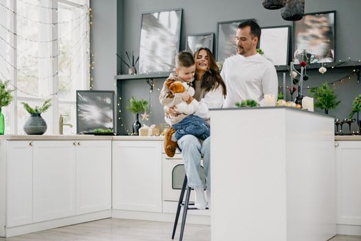 Happy young family spending time together in kitchen at home at Christmas holidays