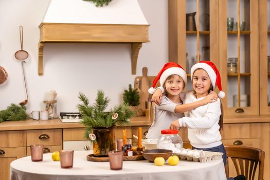 happy sisters children girls bake cookies, knead dough, play with flour and laugh in the kitchen