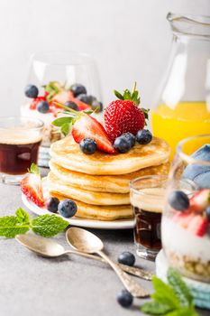 Breakfast composition with fresh pancakes and berries on light gray concrete background. Healthy food concept with copy space.
