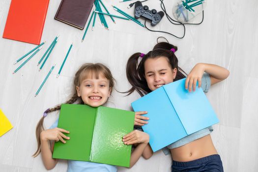 two little girls sisters reading a book lying on the floor