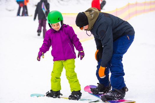 At Cold Winder Day at Mountain Ski Resort Father Teaching Little Daughter Snowboarding