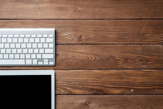 Top view of modern working place. Tablet computer and computer keyboard on vintage wooden surface. Education, creativity and innovation concept with copy space. Digital technology in modern business.