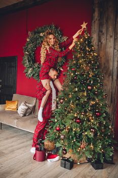 caucasian girl and her boyfriend decorates christmas tree and have fun in christmas atmosphere