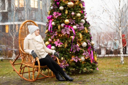 woman and photo zone christmas tree and rocking chair on the street