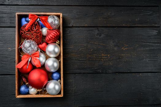 Christmas baubles and toys set, in wooden box, top view flat lay, on black wooden table background, with copy space for text