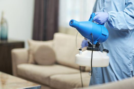 Cropped photo of man wearing protective gloves and using disinfectant in hotel room. Coronavirus and quarantine concept