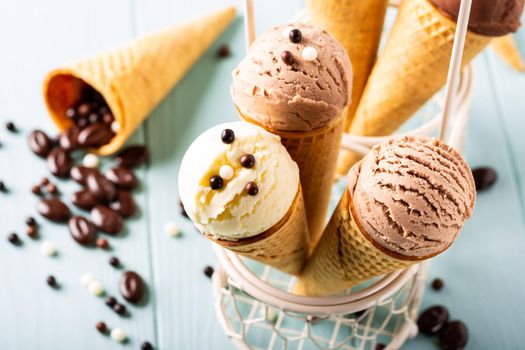 Homemade coffee, vanilla and chocolate ice cream in waffle cones on turquoise background. Healthy summer food concept.