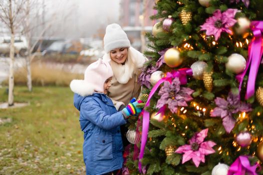 Smiling mother and daughter near Christmas tree