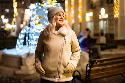 Girl walking in Christmas market decorated with holiday lights in the evening. Feeling happy in big city. Spending winter vacations in Red square, Moscow, Russia.