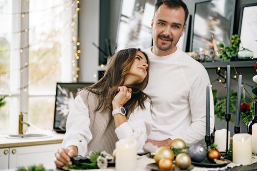 Young loving couple having good time at Christmas morning in decorated kitchen