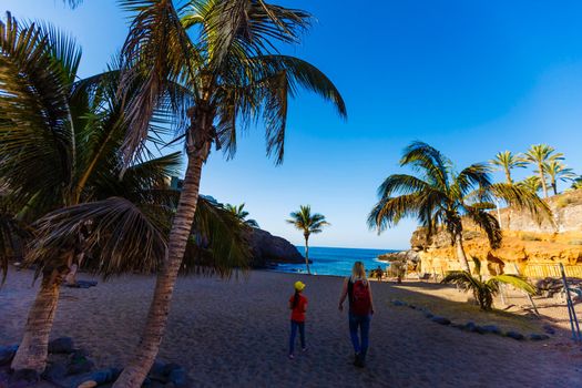 mother and daughter are walking near the ocean on the island of tenerife.