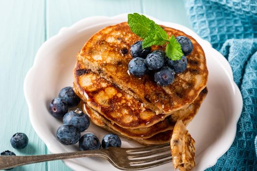 Delicious pancakes with chocolate drops, honey and blueberries. Healthy breakfast concept. High angle view